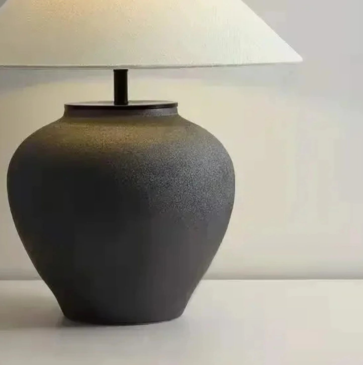 Dark ceramic table lamp with a white lampshade on a light background