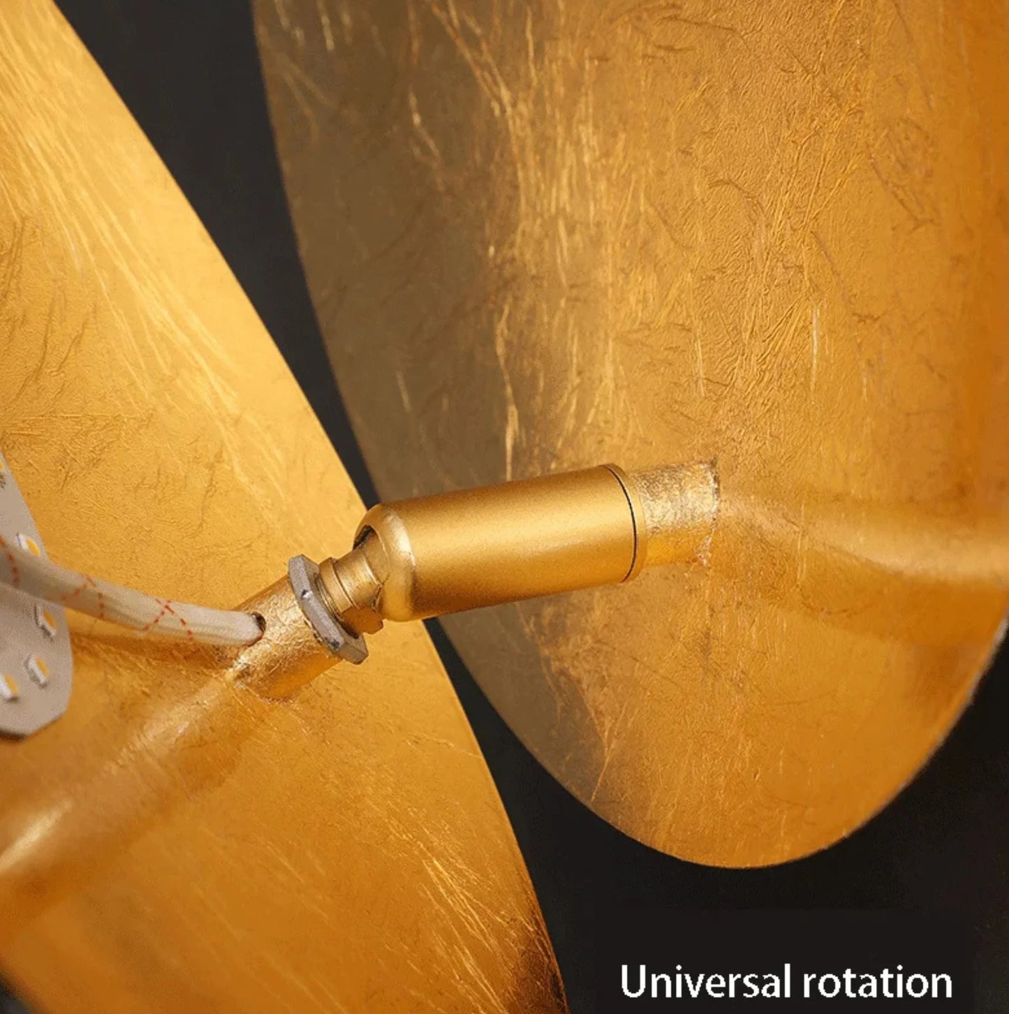 Close-up of a gold wall light with 'Universal rotation' text on a dark background