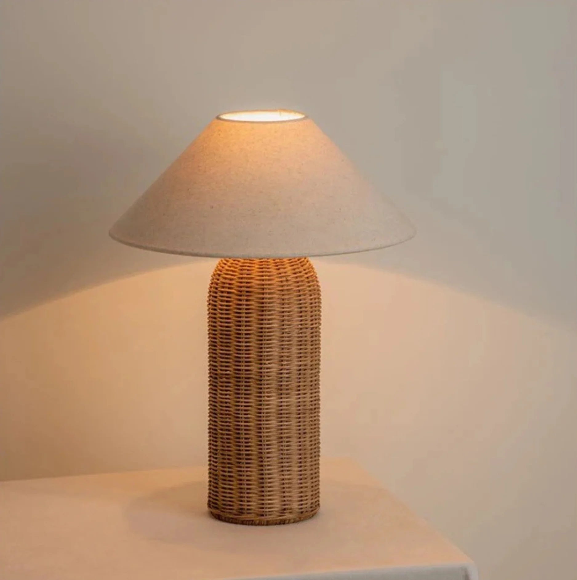 Table lamp with wicker base and beige shade on a neutral background