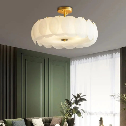 Modern ceiling light fixture in a living room with green walls and white curtains.
