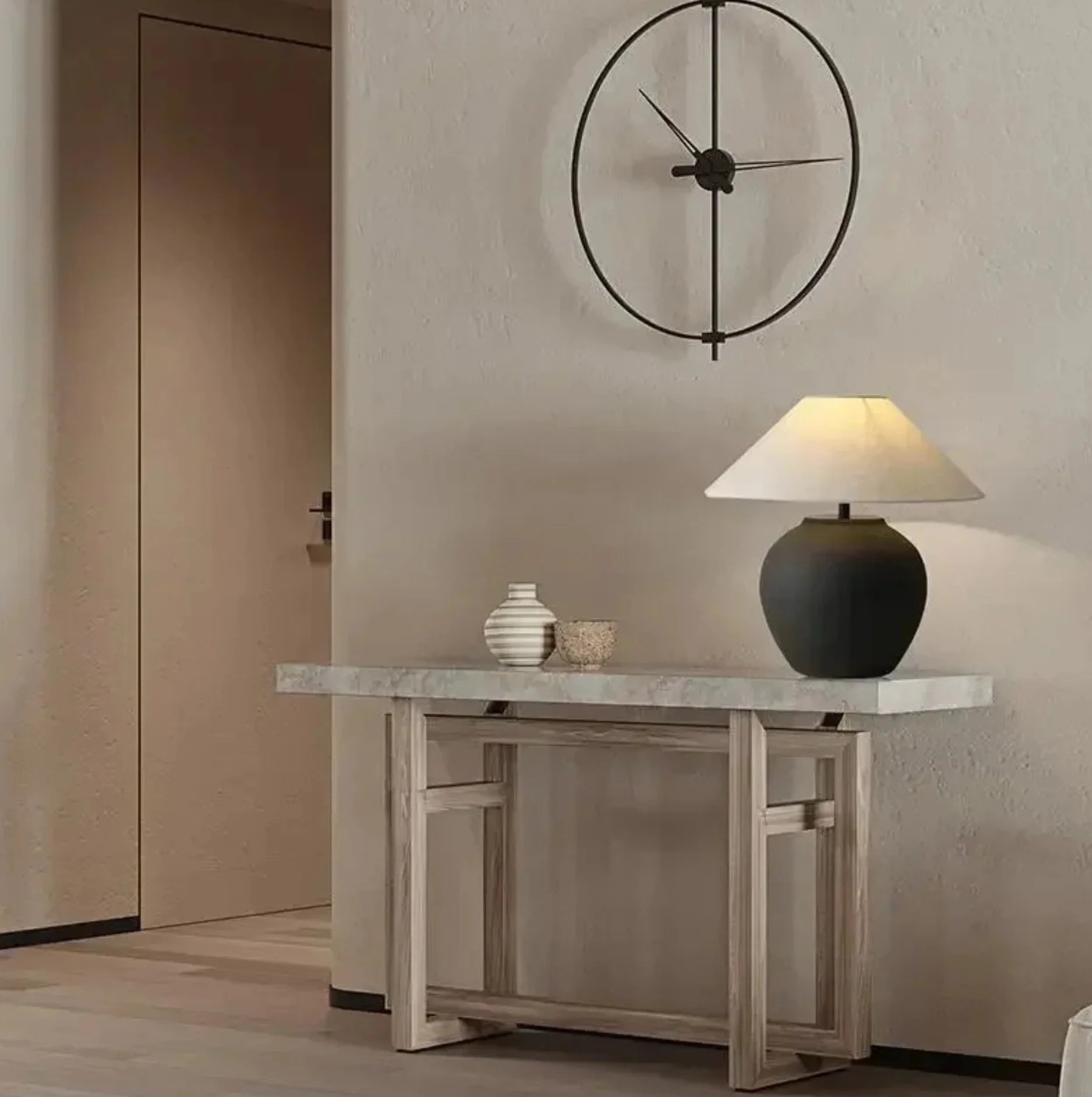 Console table with decorative items and a lamp against a neutral wall with a clock.