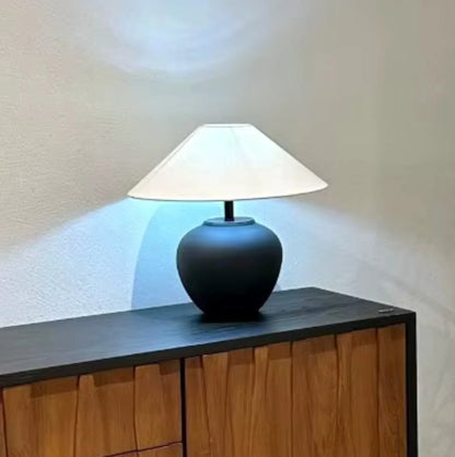 Table lamp with white shade on a wooden surface against a neutral wall