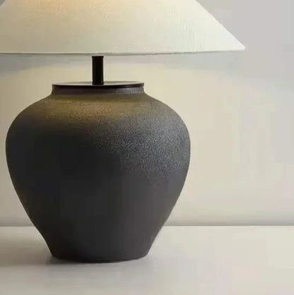 Dark ceramic table lamp with a white lampshade on a light background