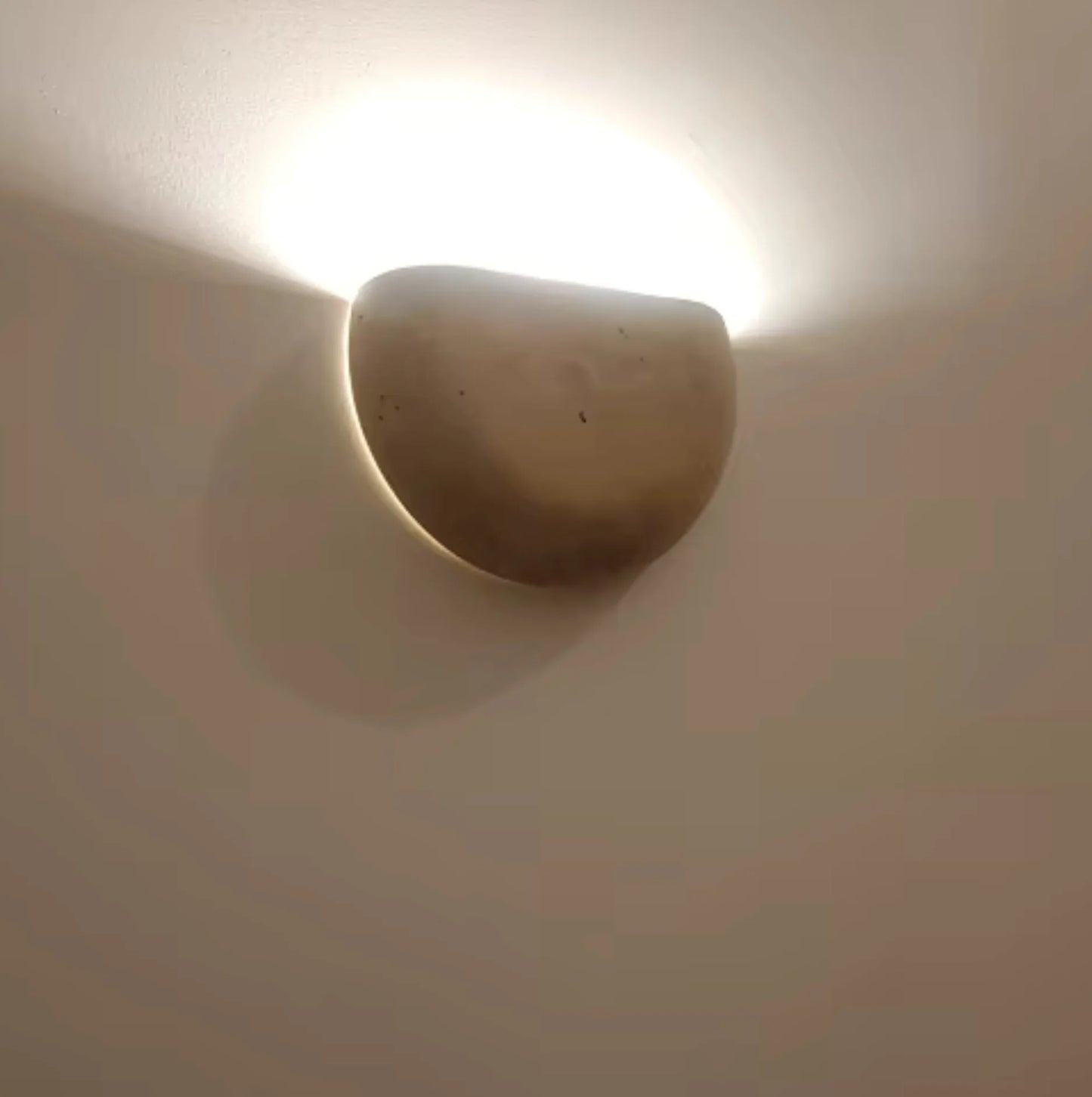 Ceramic wall sconce emitting light on a white wall