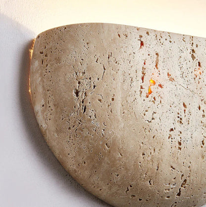 Close-up of a textured stone wall sconce on a white background