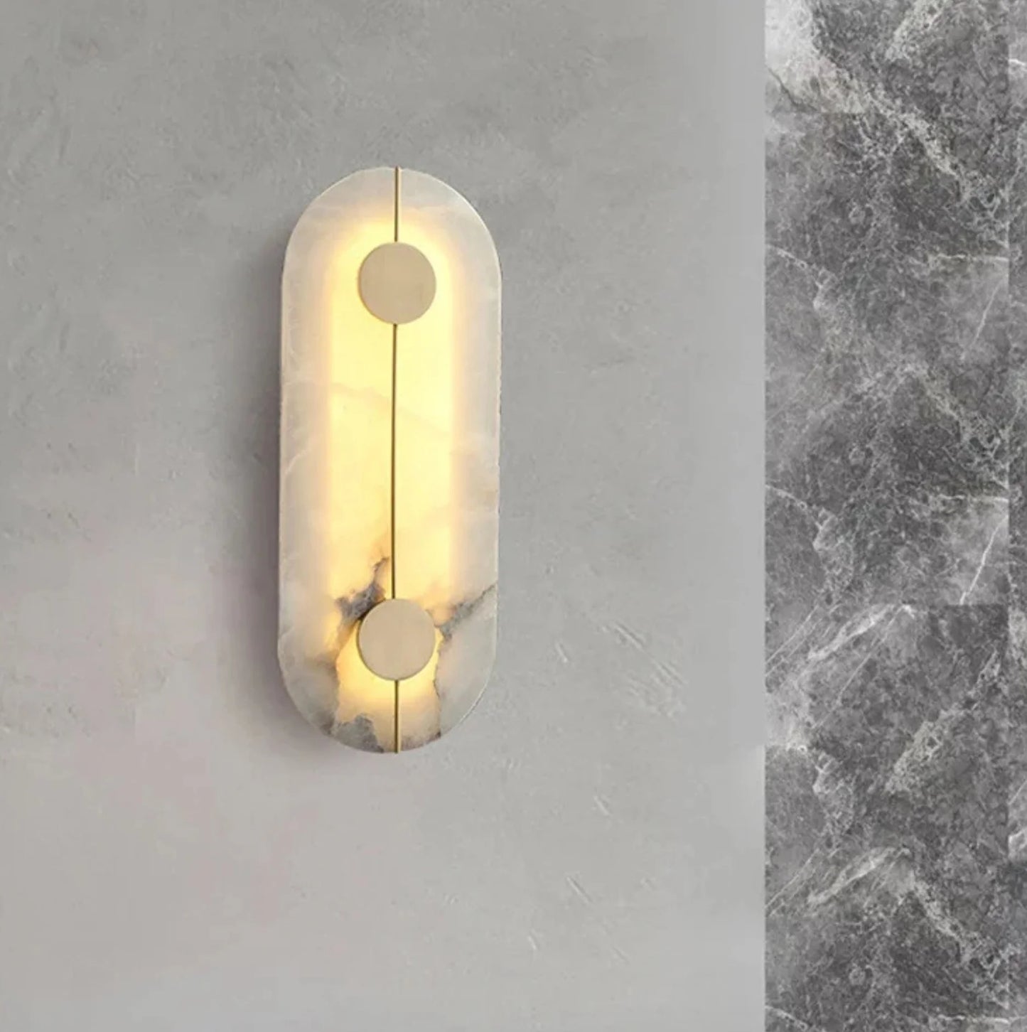 Wall light fixture on a gray wall with marble texture.