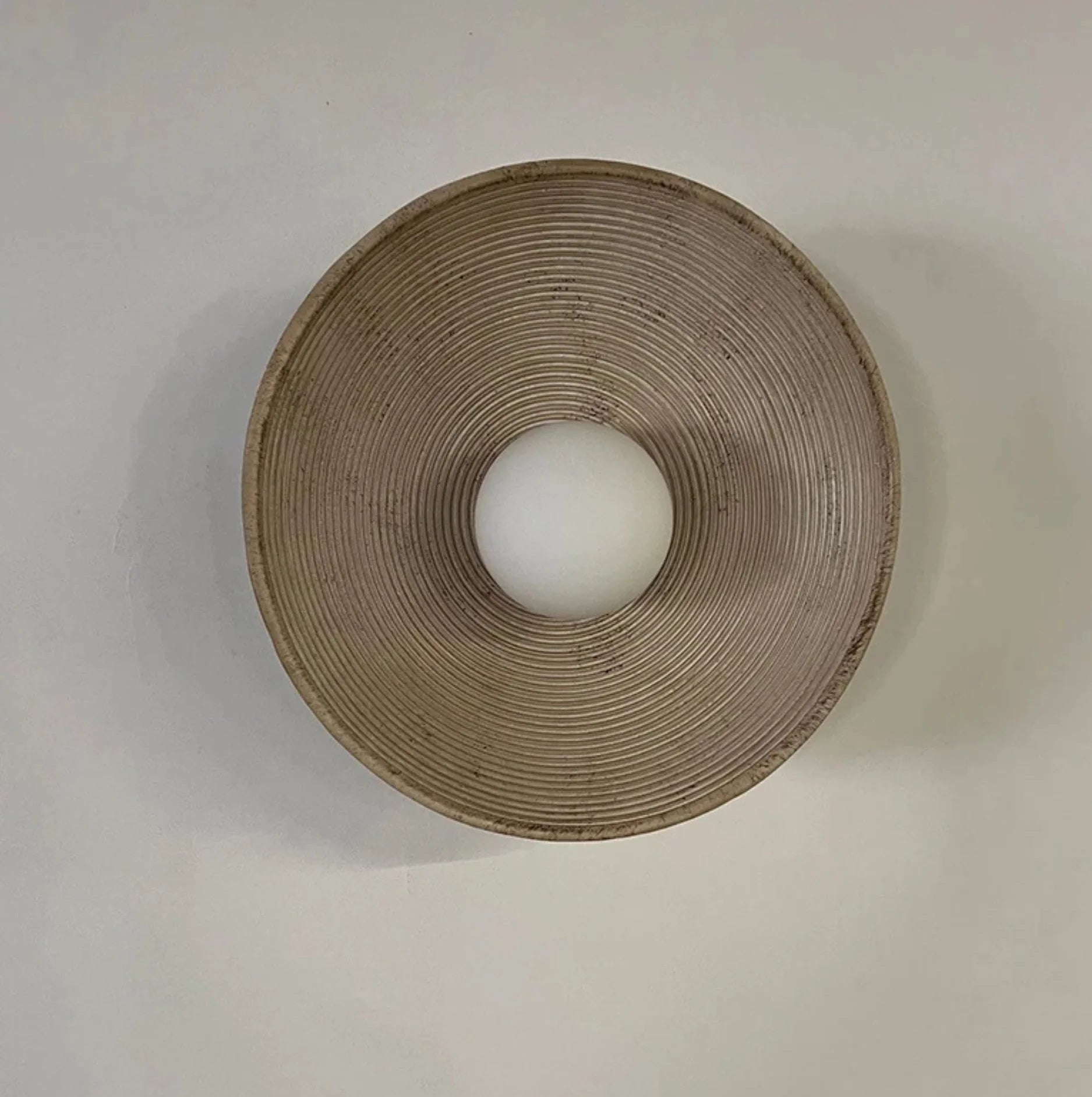 Round beige lampshade with a white bulb inside on a light gray background