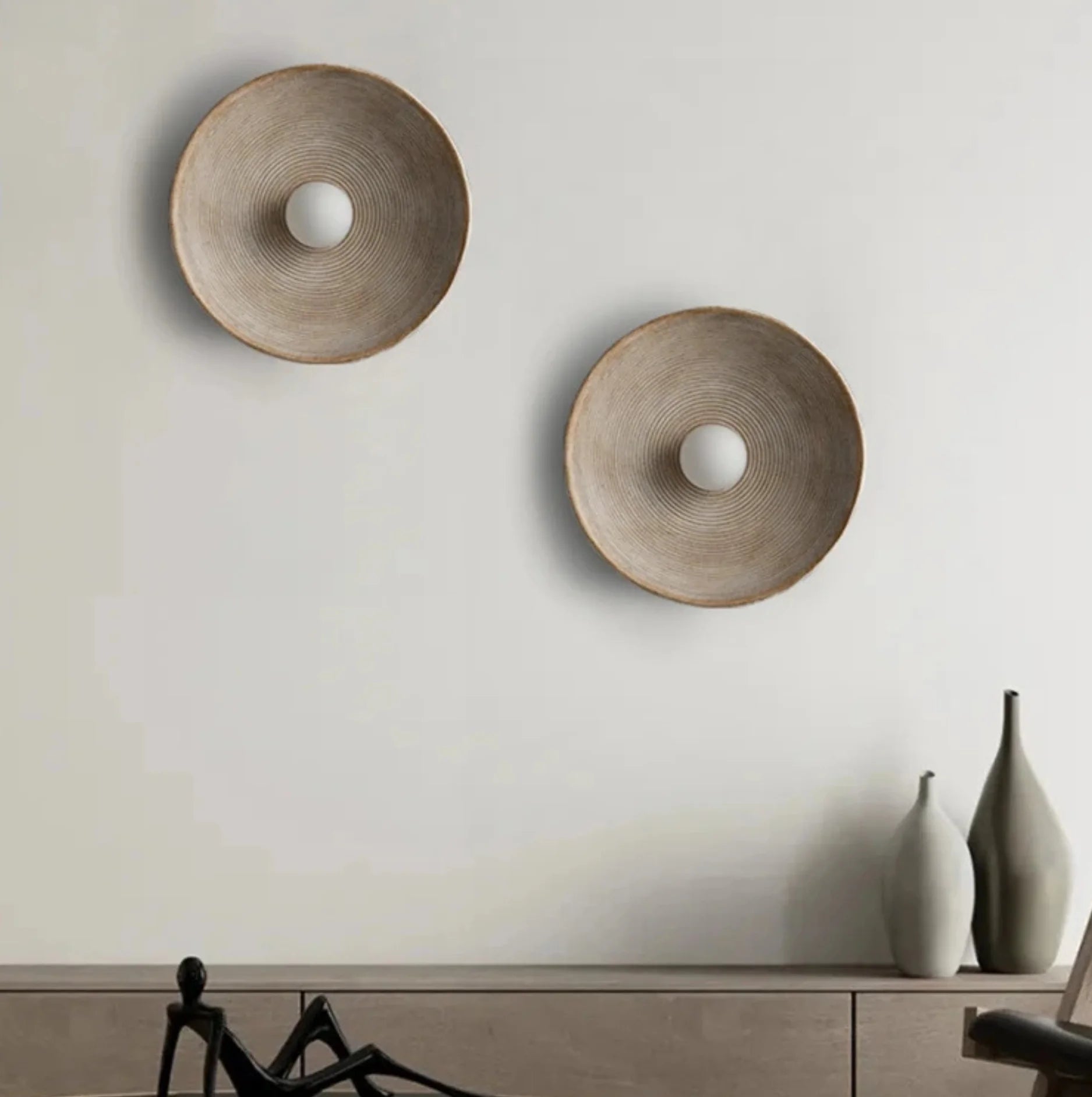 Two round wall lamps on a light gray wall with a minimal background.