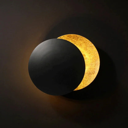 Wall light , one  side black and one gold, against a dark background.