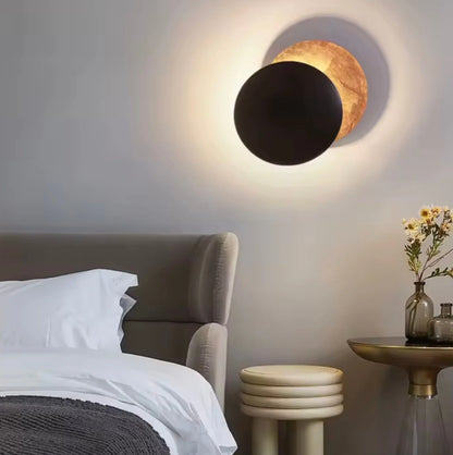 Modern wall lamp with black and gold design in a bedroom setting.