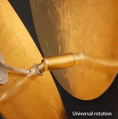 Close-up of a gold wall lighgt with 'Universal rotation' text on a dark background