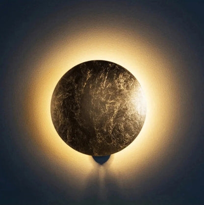 Round stone wall light fixture emitting a warm glow against a dark background
